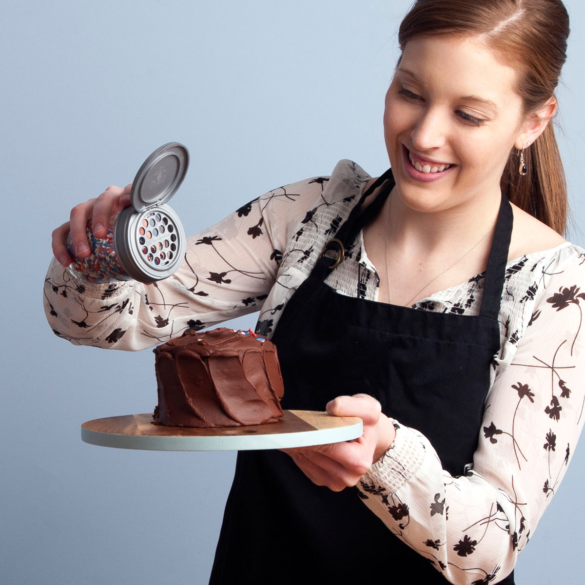A women shaking sprinkles on to a cake.
