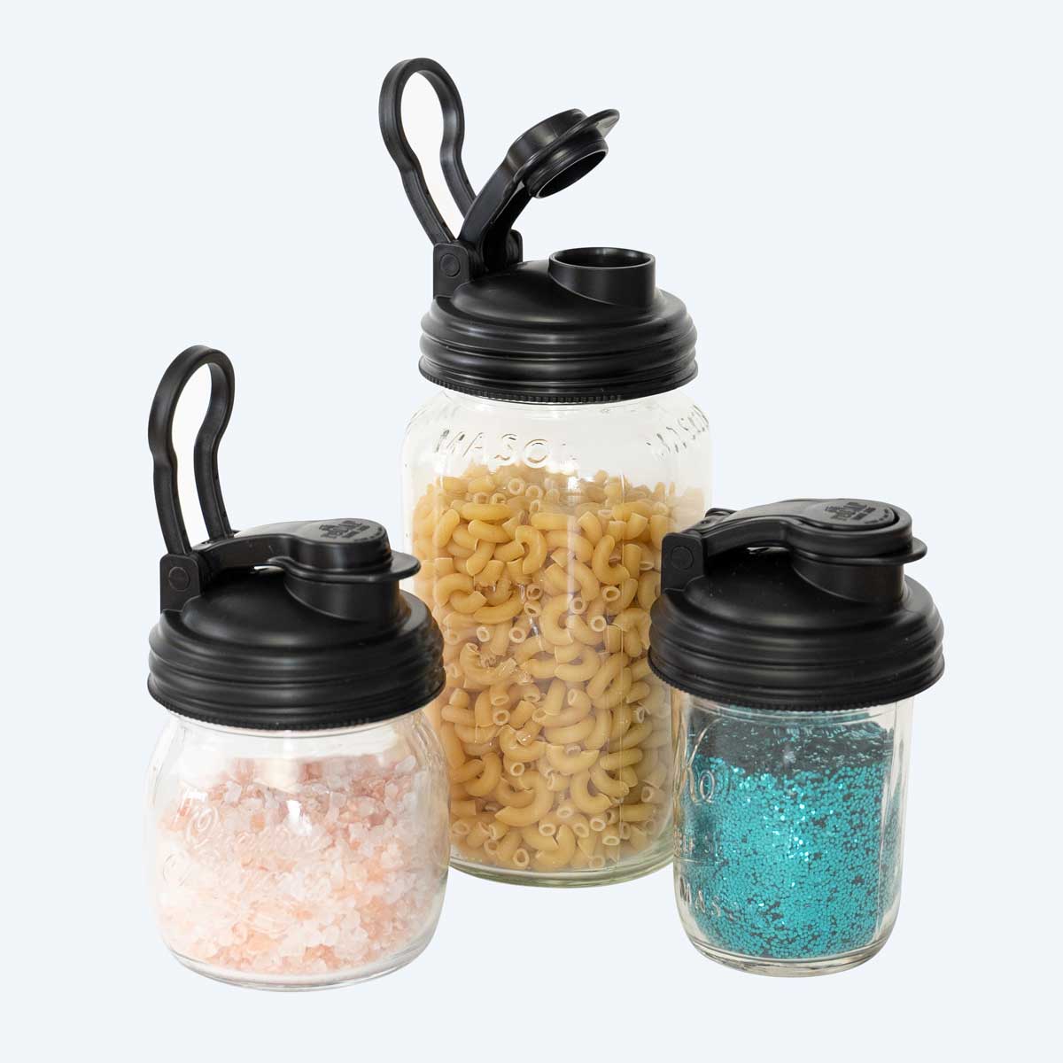 The jars full of dry goods tops with black Mason Jar POUR Lids.