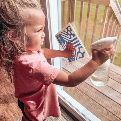 A little girl washing windows with Mason Jar Sprayer lid.