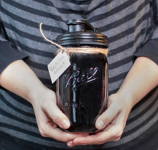 Vanilla Extract inside a jar topped with a black Mason Jar POUR Lid.